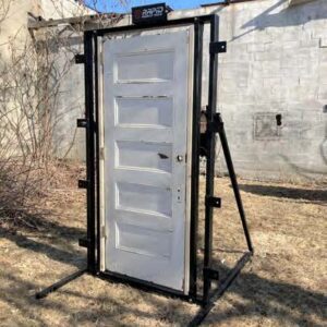 A white door is on the ground near some trees.