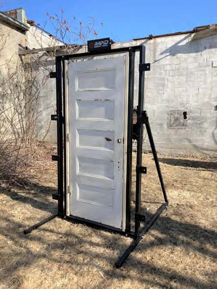 A white door is on the ground near some trees.